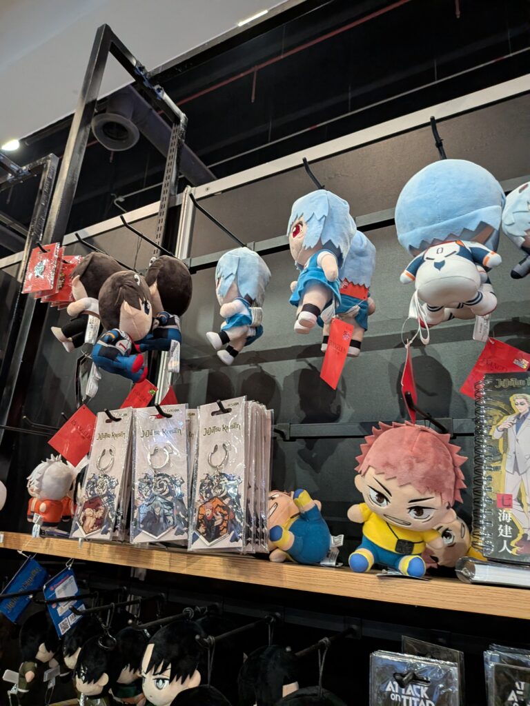アニモレの物販エリアの棚。エヴァンゲリオンや呪術廻戦のぬいぐるみ・キーホルダーグッズが並ぶ
